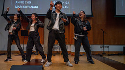 four students dancing onstage in black leather jackets